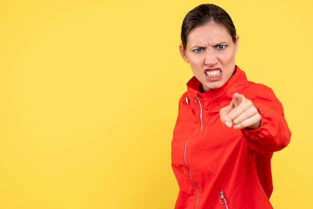 Photo gratuite vue de face jeune femme en manteau rouge en colère sur fond jaune