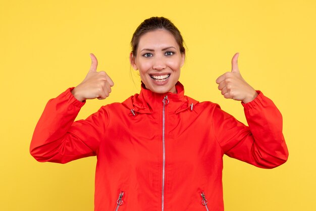 Vue de face jeune femme en manteau rouge sur fond jaune