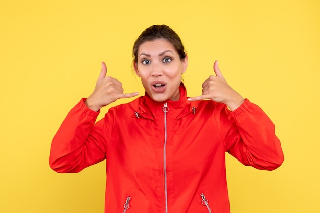 Vue de face jeune femme en manteau rouge sur fond jaune