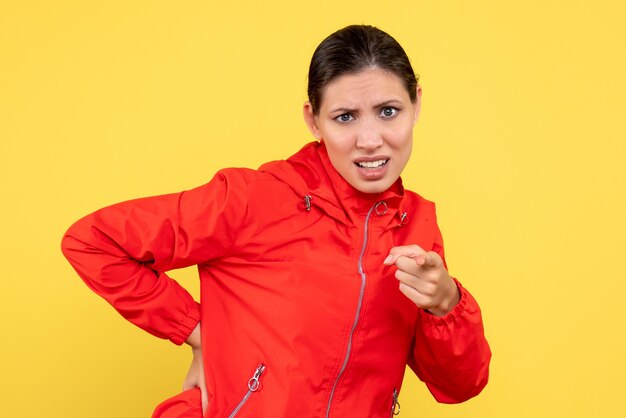 Vue de face jeune femme en manteau rouge sur fond jaune