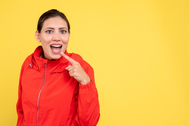 Vue de face jeune femme en manteau rouge sur fond jaune