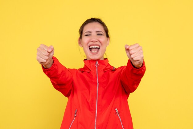 Vue de face jeune femme en manteau rouge sur fond jaune