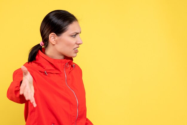 Vue de face jeune femme en manteau rouge sur fond jaune