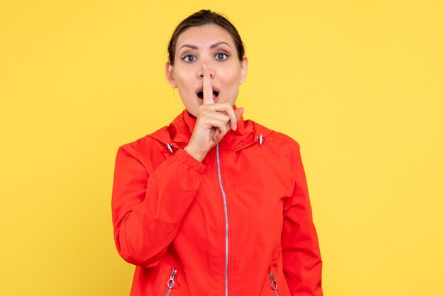 Vue de face jeune femme en manteau rouge sur fond jaune