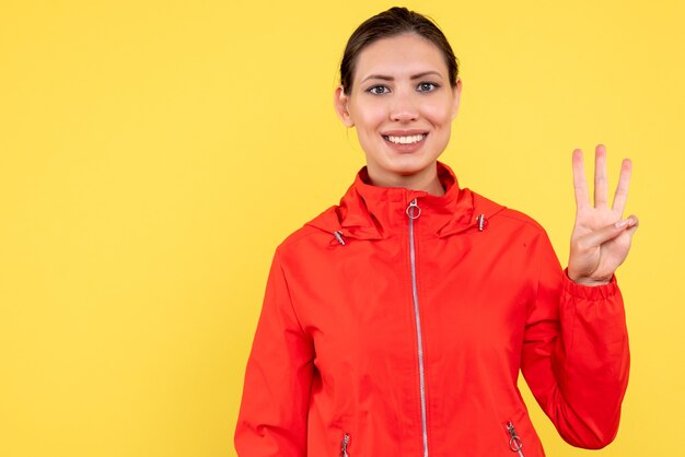 Vue de face jeune femme en manteau rouge sur fond jaune