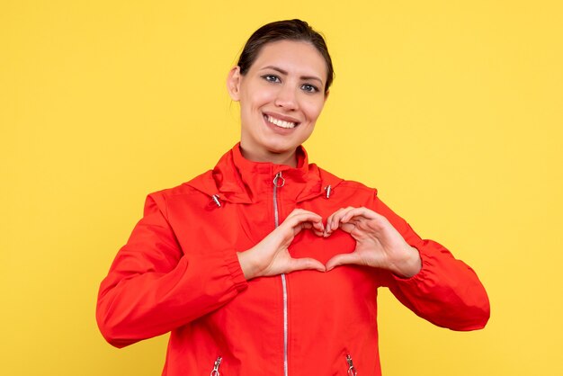 Vue de face jeune femme en manteau rouge sur fond jaune