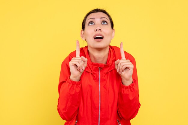 Vue de face jeune femme en manteau rouge sur fond jaune