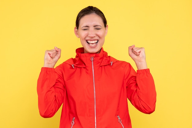 Vue de face jeune femme en manteau rouge sur fond jaune