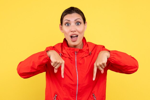 Vue de face jeune femme en manteau rouge sur fond jaune