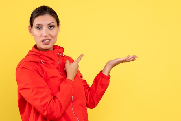 Vue de face jeune femme en manteau rouge sur fond jaune