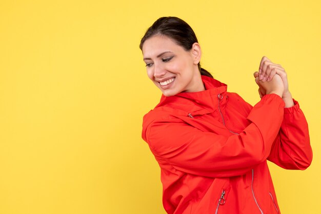 Vue de face jeune femme en manteau rouge sur fond jaune