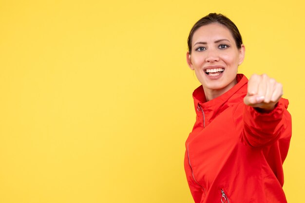 Vue de face jeune femme en manteau rouge sur fond jaune