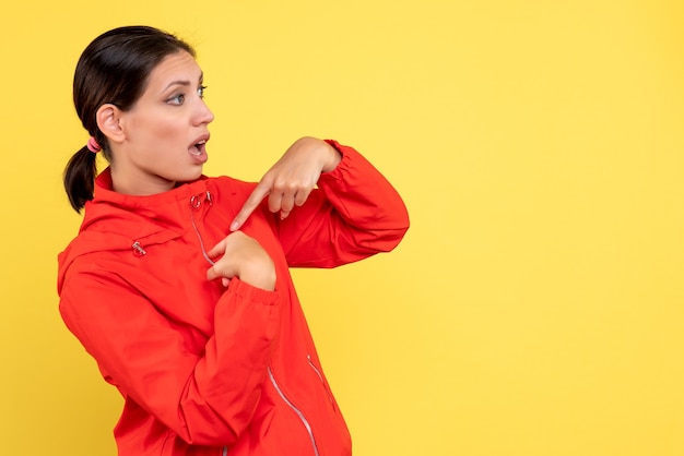 Vue de face jeune femme en manteau rouge sur fond jaune