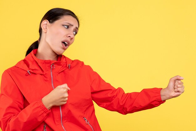 Vue de face jeune femme en manteau rouge sur fond jaune