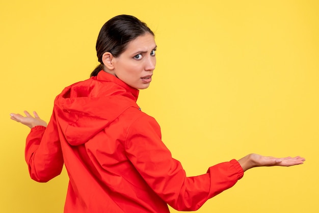 Vue de face jeune femme en manteau rouge sur fond jaune