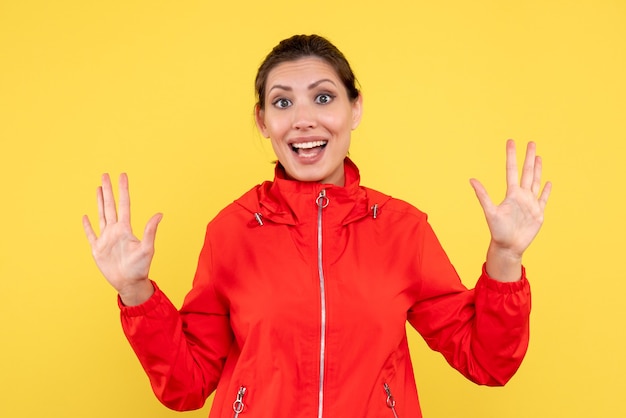 Vue de face jeune femme en manteau rouge sur fond jaune