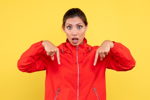 Vue de face jeune femme en manteau rouge sur fond jaune