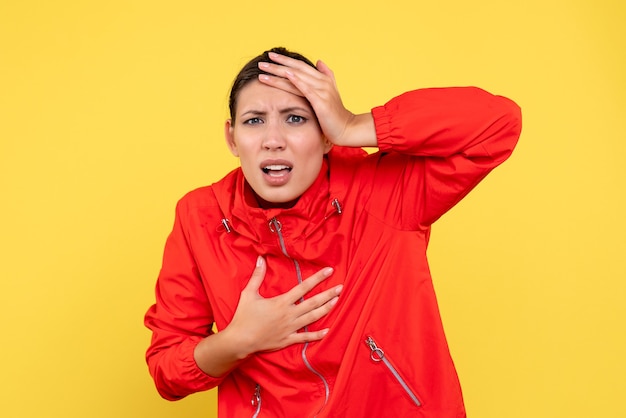 Vue de face jeune femme en manteau rouge sur fond jaune