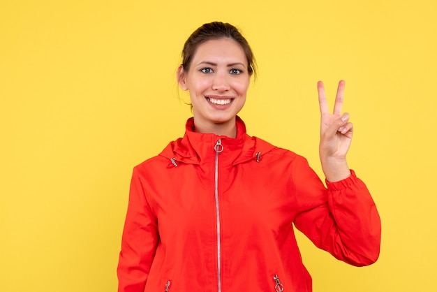 Vue de face jeune femme en manteau rouge sur fond jaune