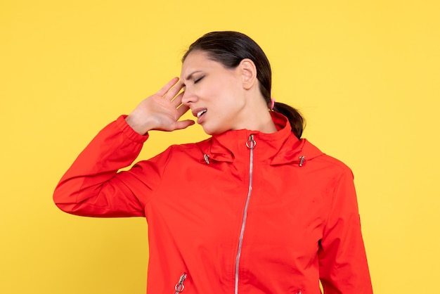 Vue de face jeune femme en manteau rouge sur fond jaune