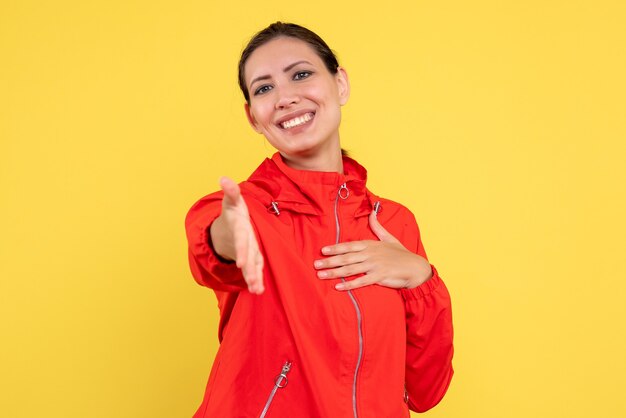 Vue de face jeune femme en manteau rouge sur fond jaune