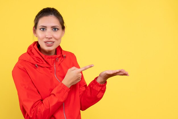 Vue de face jeune femme en manteau rouge sur fond jaune