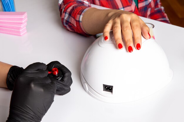 Photo gratuite une vue de face jeune femme manucure avec des gants noirs faisant manucure sur blanc
