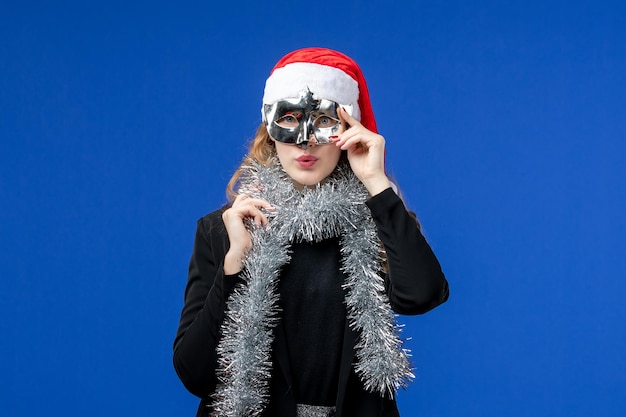 Vue de face d'une jeune femme avec un masque d'argent sur un mur bleu