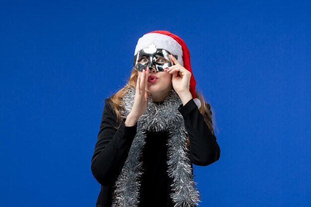 Vue de face d'une jeune femme avec un masque d'argent sur un mur bleu