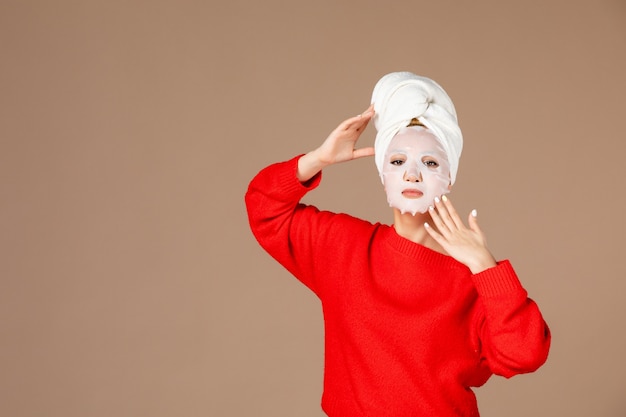 Vue de face jeune femme avec masque sur fond rose