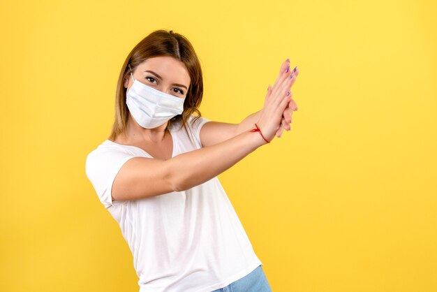 Vue de face de la jeune femme en masque sur un mur jaune