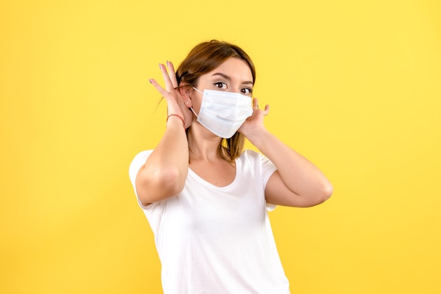 Vue de face de la jeune femme en masque sur un mur jaune