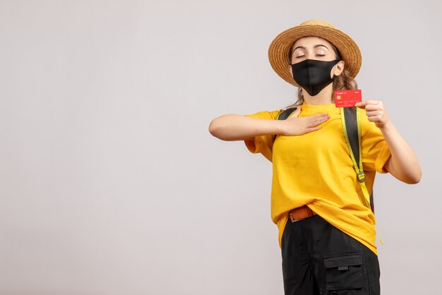 Vue de face jeune femme avec masque noir tenant une carte mettant la main sur sa poitrine