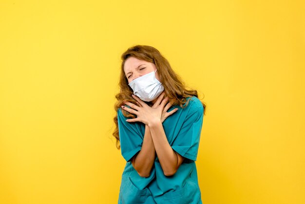 Vue de face jeune femme médecin ayant des problèmes respiratoires sur l'espace jaune