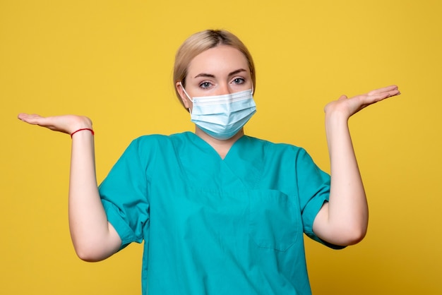 Vue De Face De La Jeune Femme Médecin En Chemise Médicale Et Masque Stérile Sur Mur Jaune