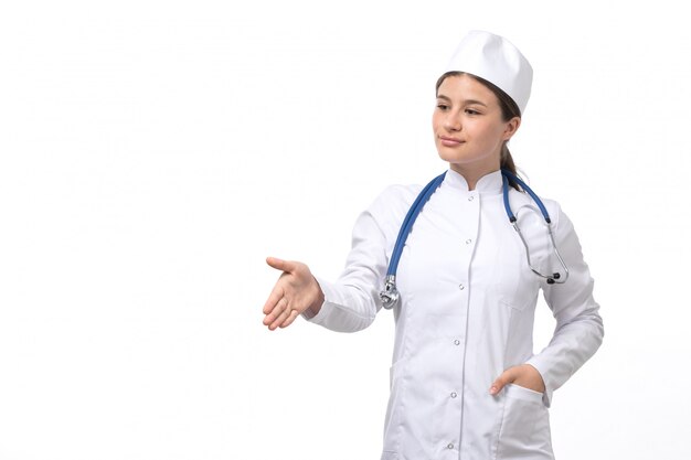 Une vue de face jeune femme médecin en costume médical blanc avec stéthoscope bleu se serrant la main