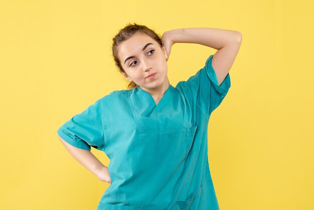 Vue de face jeune femme médecin en costume médical sur fond jaune