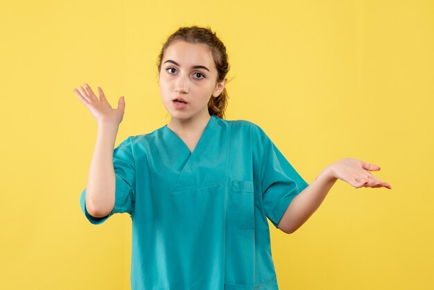 Vue de face jeune femme médecin en costume médical sur jaune