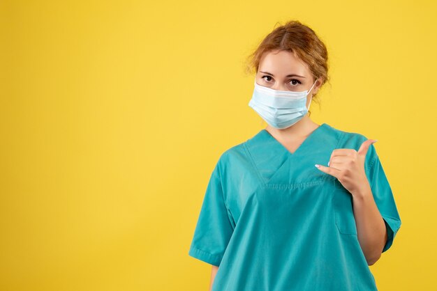 Photo gratuite vue de face de la jeune femme médecin en costume médical et masque sur mur jaune