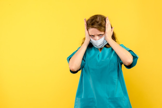 Vue de face jeune femme médecin en masque sur espace jaune