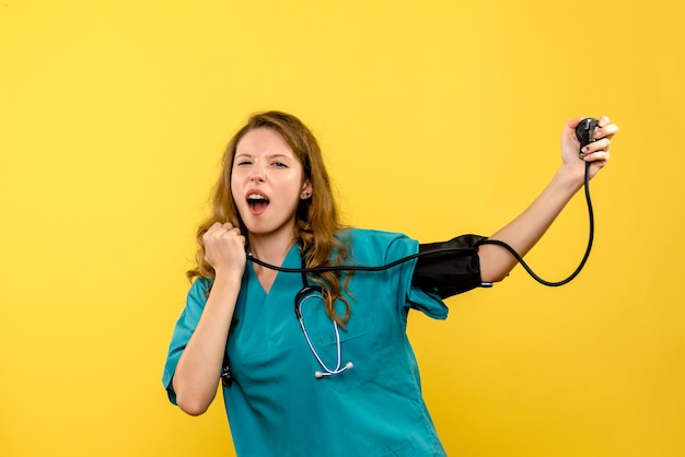 Vue de face jeune femme médecin mesurant la pression sur l'espace jaune