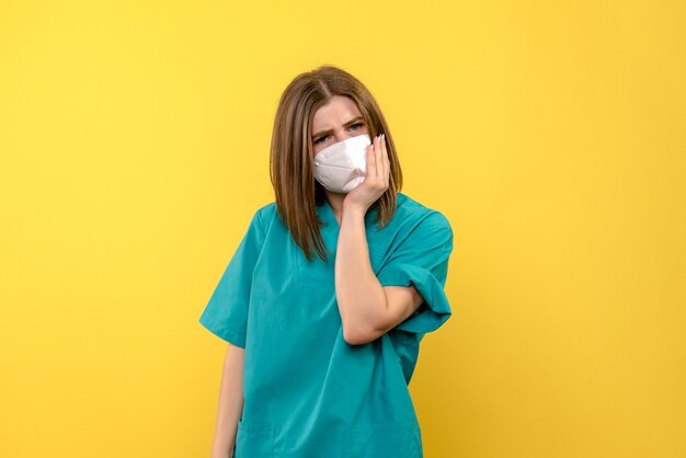 Vue de face de la jeune femme médecin sur mur jaune