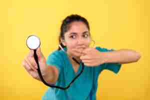 Photo gratuite vue de face de la jeune femme médecin pointant sur le stéthoscope sur mur jaune