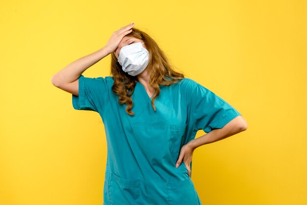 Vue de face jeune femme médecin a souligné en masque sur l'espace jaune