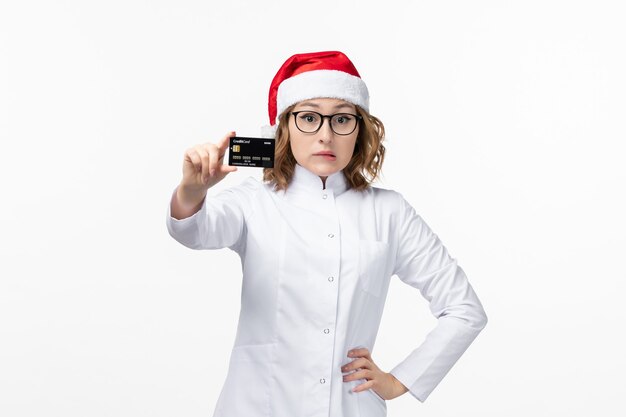 Vue de face jeune femme médecin tenant une carte bancaire sur mur blanc vacances infirmière nouvel an