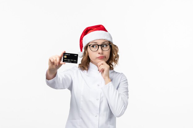 Vue de face jeune femme médecin tenant une carte bancaire sur plancher blanc argent infirmière nouvel an