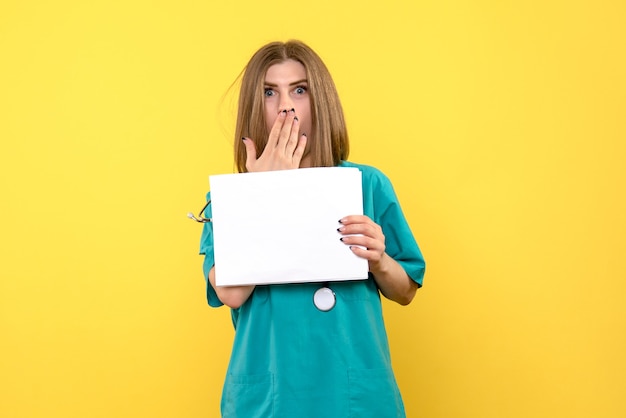 Vue De Face De La Jeune Femme Médecin Tenant Des Fichiers Sur Mur Jaune