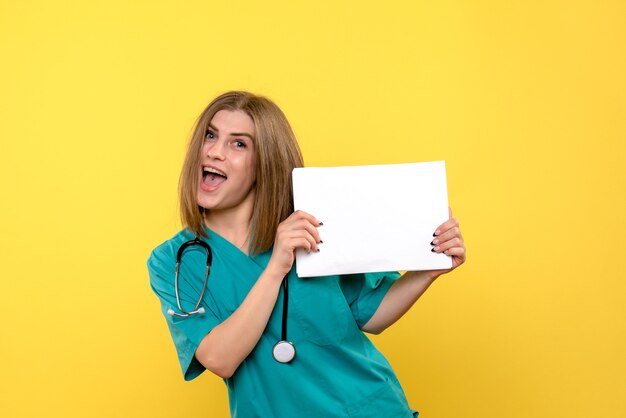 Vue de face de la jeune femme médecin tenant des fichiers sur mur jaune