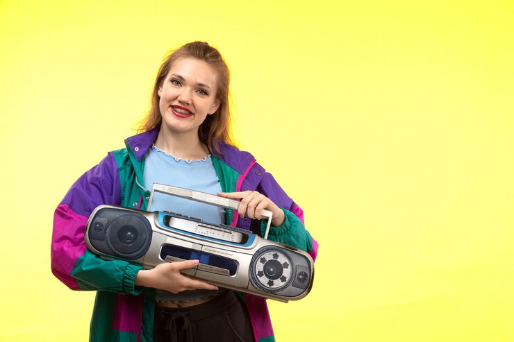 Photo gratuit une vue de face jeune femme moderne en chemise bleue pantalon noir veste colorée souriant posant tenant un magnétophone