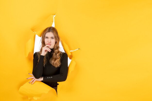 Vue de face jeune femme sur mur déchiré jaune